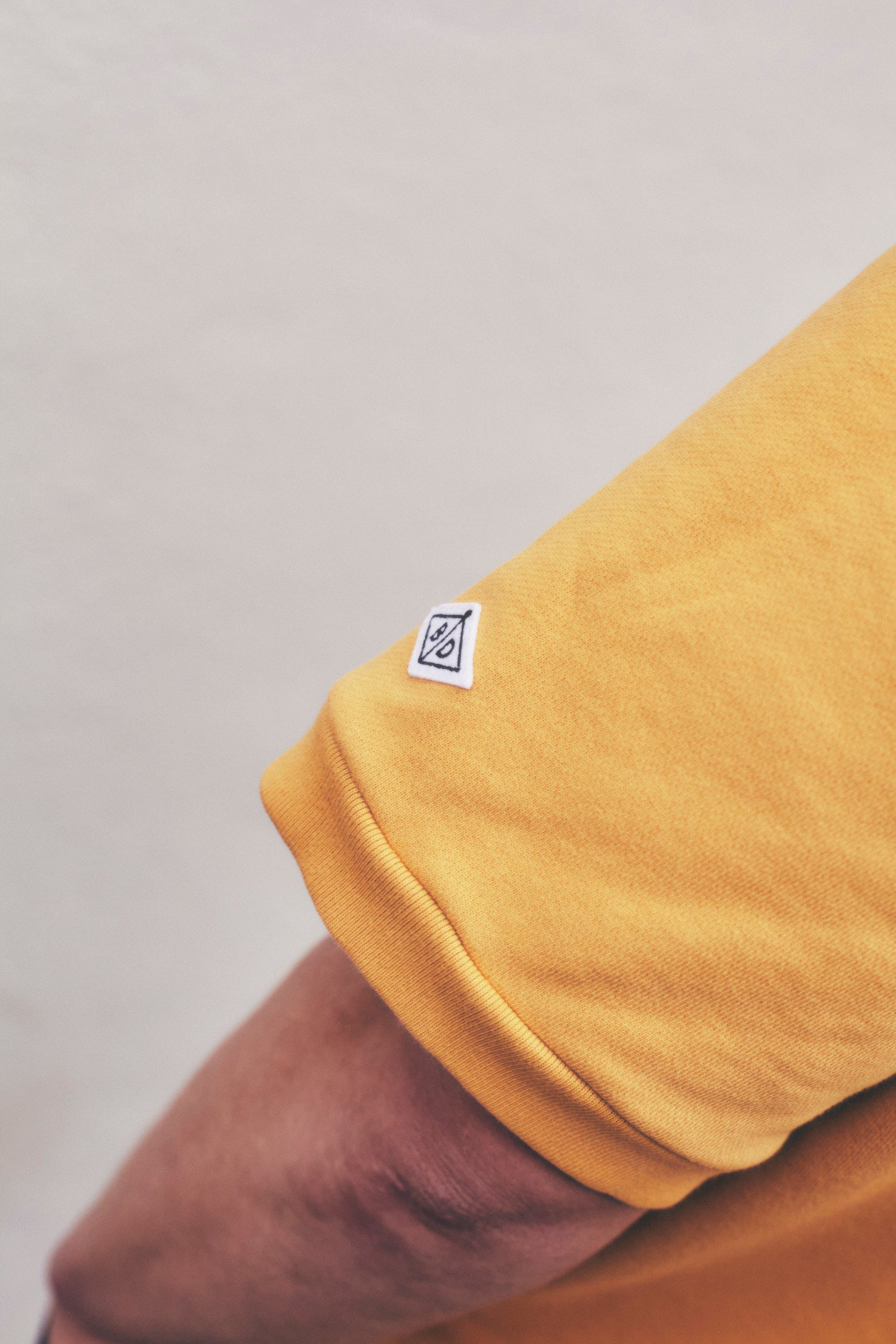 The Fife golf polo in cheese toastie yellow. sleeve showing logo